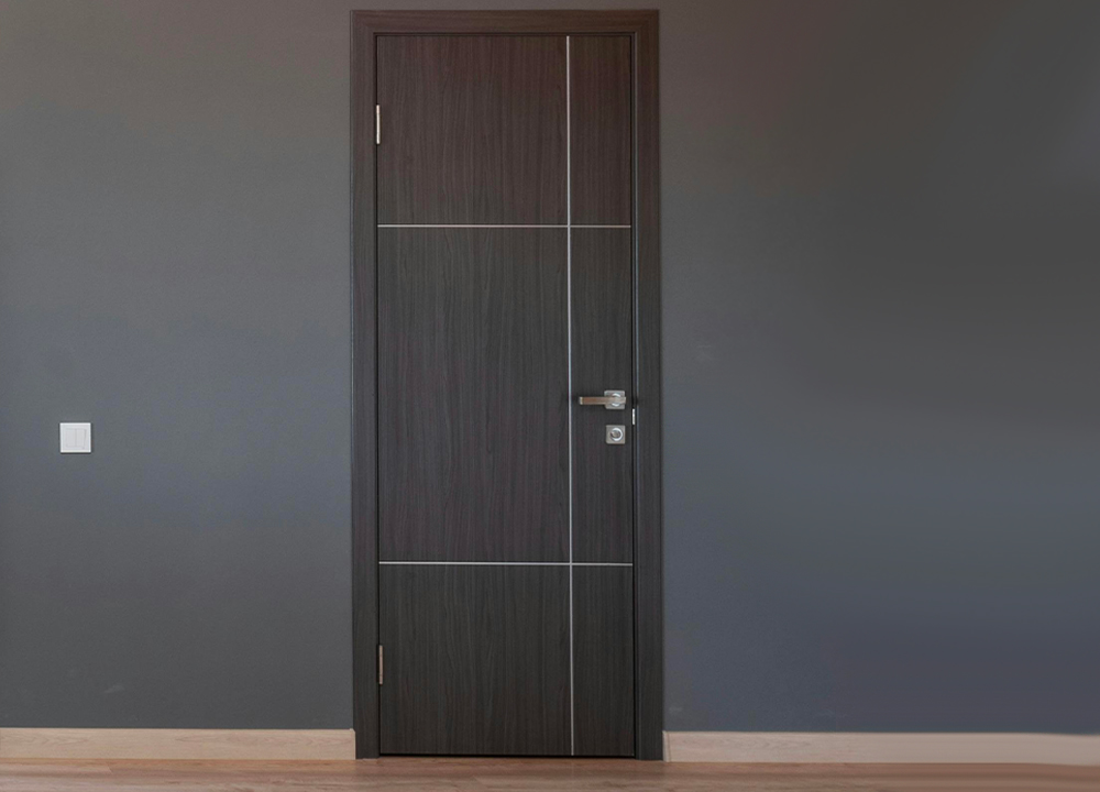 Porta interna moderna con finitura materica effetto legno scuro e inserti geometrici in metallo, montata su parete grigio antracite.