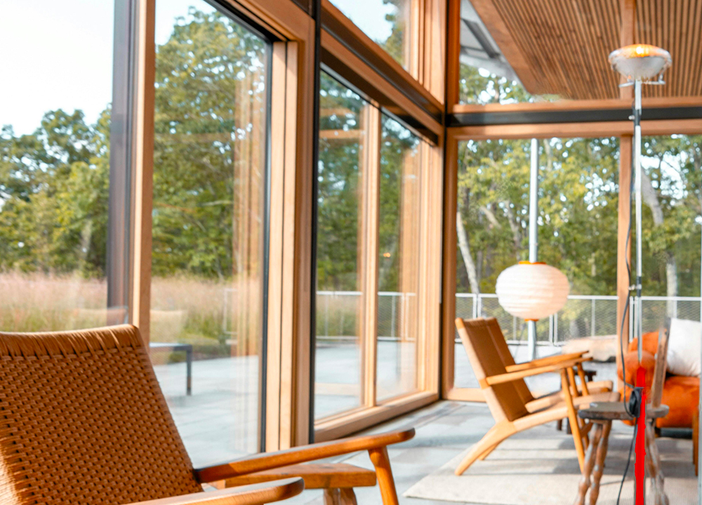 Ampie vetrate con serramenti in legno-alluminio in una zona living moderna e luminosa con vista sul verde