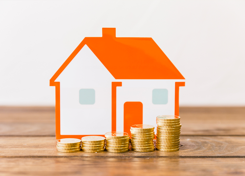 Pile di monete crescenti davanti a una casa stilizzata, simbolo di risparmio grazie ai bonus infissi e alle detrazioni fiscali