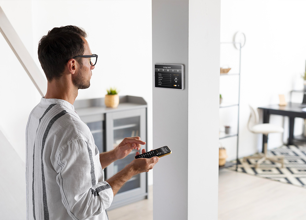 Uomo che gestisce un impianto domotico tramite smartphone e pannello touch a muro in una casa moderna
