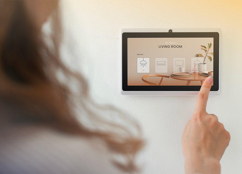 Donna che controlla i dispositivi della smart home tramite pannello domotico touch screen nel soggiorno
