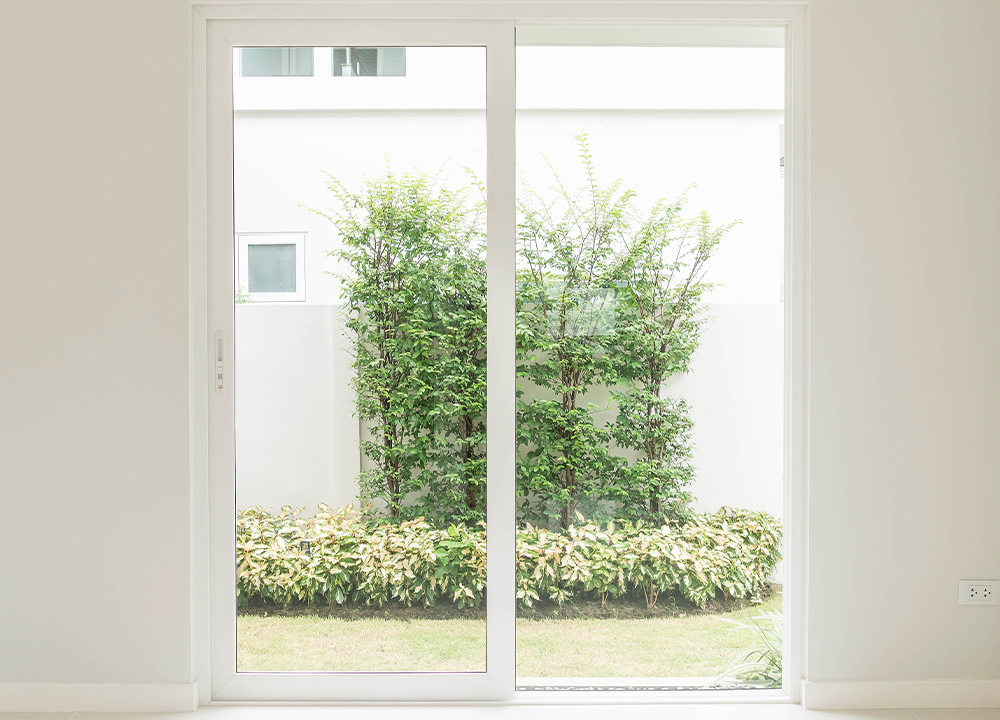 Porta finestra in PVC bianco con vista su giardino verde