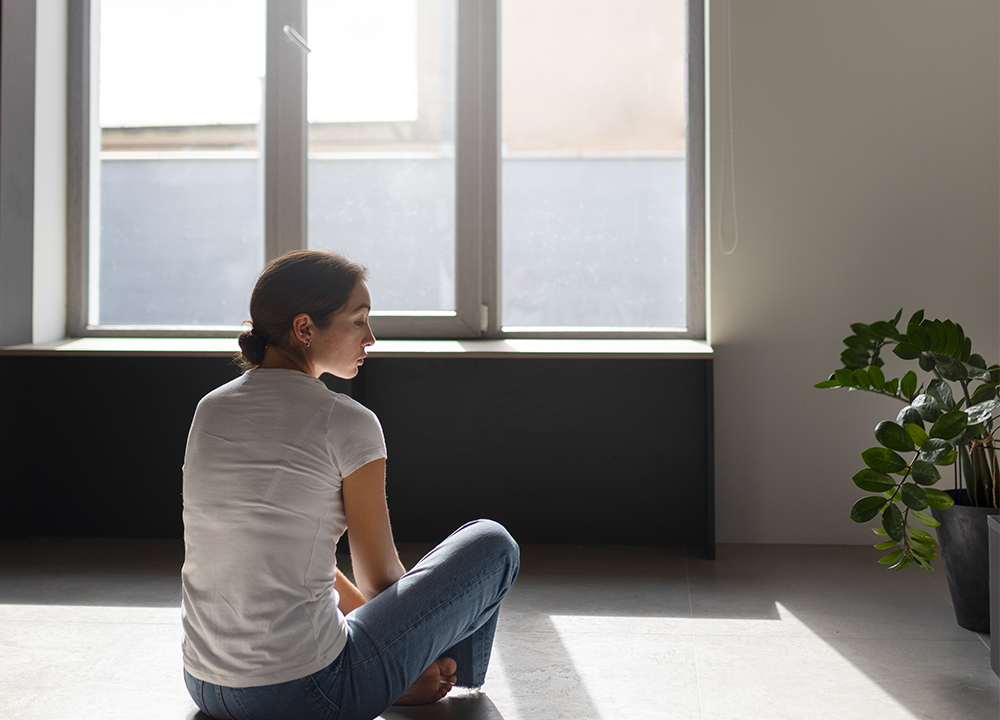 Donna seduta vicino a finestra con vetro basso emissivo che riflette la luce e trattiene il calore.