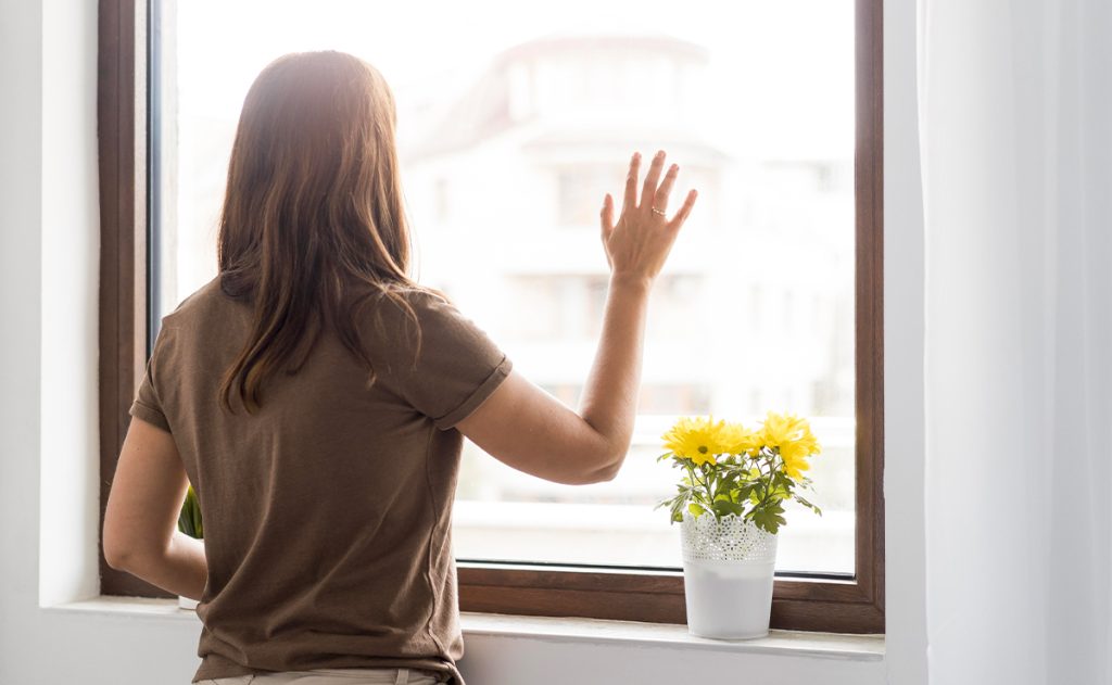 Donna che appoggia la mano su una finestra con vetro selettivo