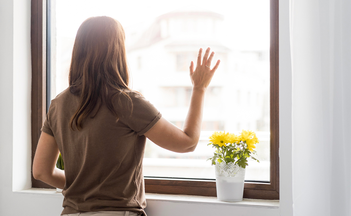 Donna che appoggia la mano su una finestra con vetro selettivo