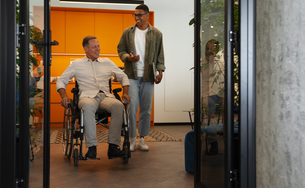 Uomo in sedia a rotelle che attraversa una soglia con infissi accessibili